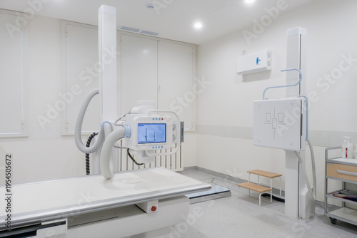 Bright radiology room with digital X ray equipment, detector panel and exam table in modern medical interior for diagnosis.