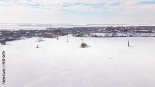 Aerial drone footage of snow covered field approaching village in Romania