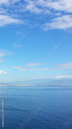 Tranquil seascape with clear blue water and a distant coastline under a partly cloudy sky in the Bay of Naples, Italy.
