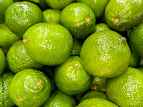 A close-up view of several bright green limes piled together, showing their waxy skin texture.