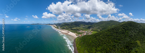 Aerial panorama of the tropical beach, little town and hidden in the green hilly terrain. Town of Siriu, Santa Catarina, Brazil