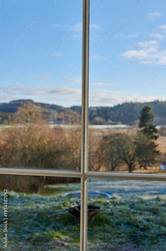 Obraz premium Window, frame and view of field in countryside with blue sky, trees and outdoor landscape. Background, empty and glass pane with scenery of meadow, environment and nature for season in Denmark