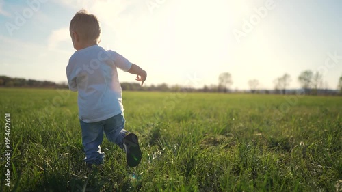 Young boy running through field. Silhouette of baby running in the grass on a park. A child running in the park at sunset. A young lad sprinting across a field lifestyle.