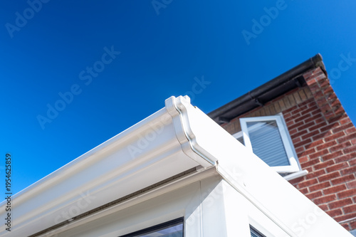 Fotografi Close-up of white plastic guttering seen on a conservatory which extends from the main house