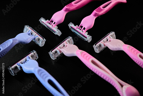 Various razors in different colors laid out on a black surface in a simple arrangement