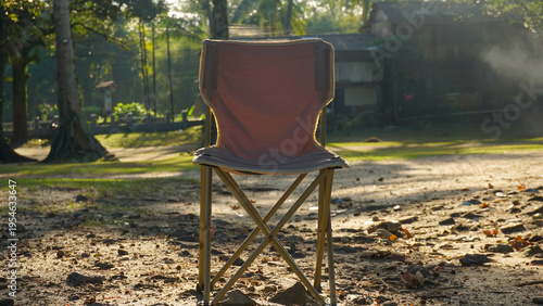 Foldable camping chair placed outdoors on rocky ground with warm sunlight, creating a relaxing and peaceful nature setting.