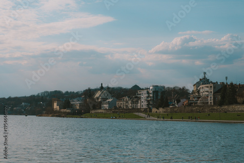 Scenic view of a European city skyline with a river and cloudy sky on a bright day