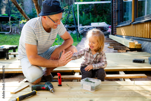 Foto Joyful father and little child building a wooden patio deck together