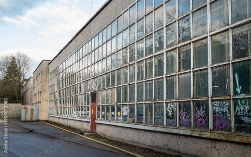 Tableau sur toile Exterior view of an old industrial building with a long glass window facade covered in graffiti
