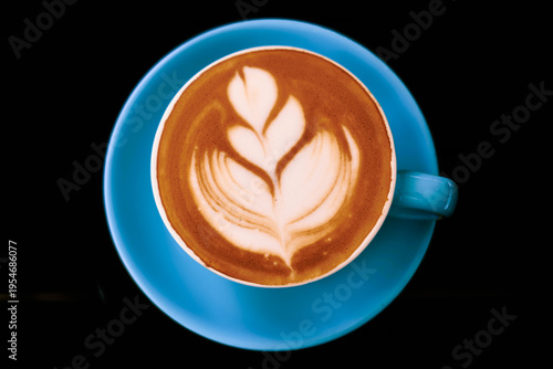 Latte with decorative milk foam in vibrant blue cup