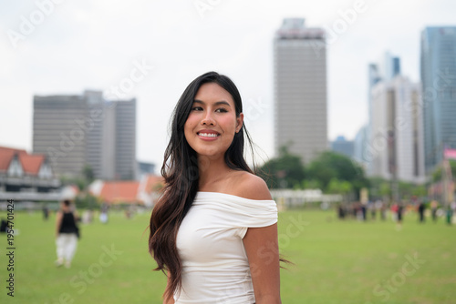Canvas Print Cute woman smiling outdoors at Merdeka Square with Kuala Lumpur city skyline and