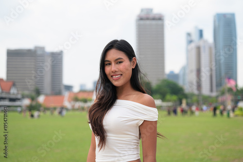 Canvas Print Cute woman smiling outdoors at Merdeka Square with Kuala Lumpur city skyline and