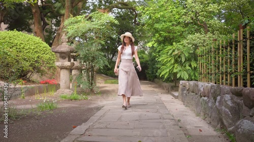 Slow motion showing a woman visiting Shrine in Fukuoka, Japan, walking through the courtyard surrounded by sacred architecture and peaceful daylight