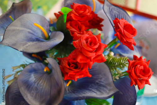 Φωτογραφία Vivid red roses and deep purple blue calla lilies form a striking artificial floral arrangement suggesting gentle movement in this video