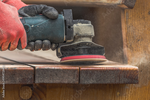 Grinding tool for woodworking in male hands. Construction equipment. Woodworking. Furniture restoration stage. Rough surface. Clean off the old layer. Hardworking master. Carpentry work.