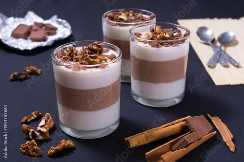 Delicious dessert cups with chocolate, jelly, and nuts on a black table