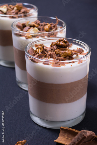 Chocolate dessert served in clear glasses with layers of jelly and toppings on a dark background