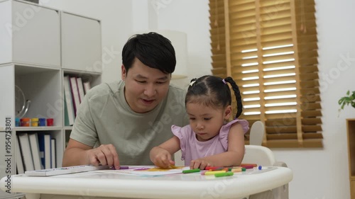 father and child girl drawing and painting with colorful oil pastels on paper at home