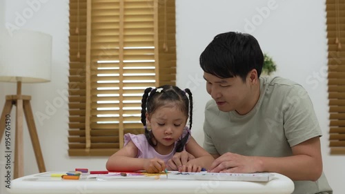 father and child girl drawing and painting with colorful oil pastels on paper at home