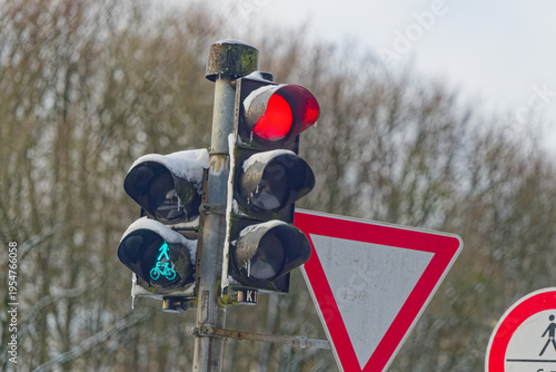 Traffic light with red stop signal and green pedestrian bicycle sign in winter