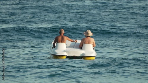 Pedal boat, couple, sea. Senior tourists enjoy a relaxing summer vacation on a pedalo in the ocean