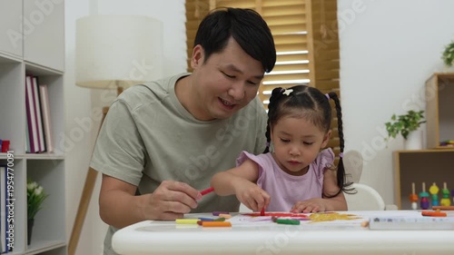 father and child girl drawing and painting with colorful oil pastels on paper at home