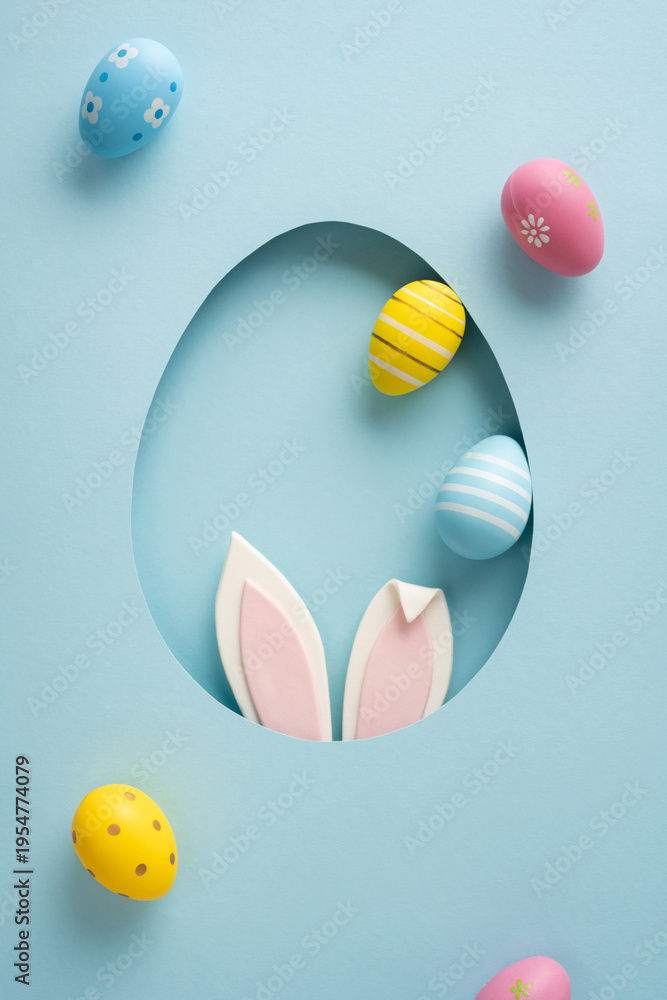 Fototapeta premium Playful vertical pastel Easter eggs and bunny ears peek through a paper cutout creating a cheerful scene for a happy Easter celebration and greeting