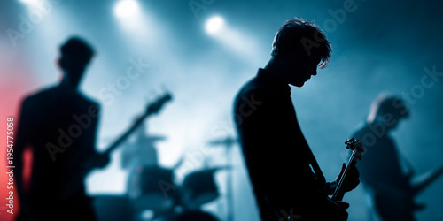 A band performing on stage in a hazy atmosphere with the band members playing guitar and bass. The stage is illuminated by spotlights