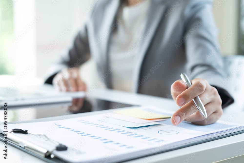 Fototapeta premium Businesswoman analyzing financial report with business document on office desk, marketing research and planning
