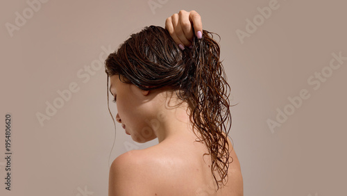 Foto Woman holding wet curly hair in ponytail after washing
