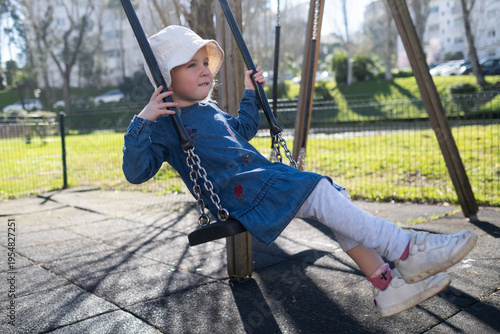 Little 4 year old girl swinging happily on a swing outdoors