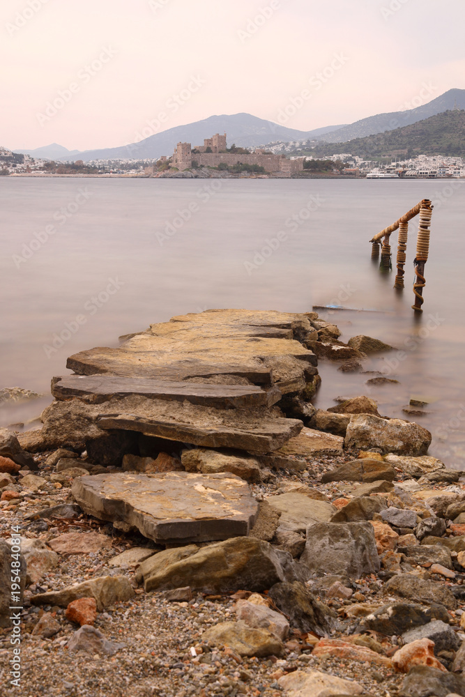 Fototapeta premium Abandoned pier and Panoramic view of Bodrum city, Turkey and Saint Peter Castle and marina. Summer landscape, popular travel destination. Selective Focus. Long Exposure shoot. tranquility scene.