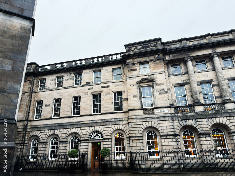 Obraz premium Historic stone Georgian building facade in West Parliament Square, Edinburgh, Scotland, UK with arched windows and classical columns on a rainy day