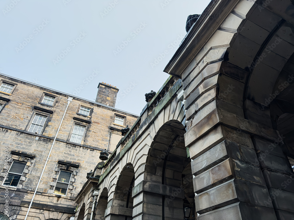 Fototapeta premium Historic stone arches and Georgian building facade in Edinburgh, Scotland, UK low angle architectural detail of classic urban courtyard masonry
