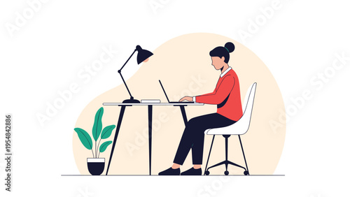 Focused professional woman sits at her minimalist desk and works on a laptop with a desk lamp providing warm light.