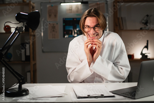 Funny cunning doctor or male nurse having evil plan, scheming something working during night shift at hospital