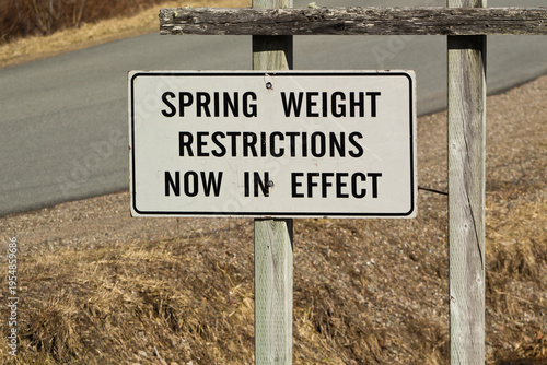 Fotografie Roadside sign indicating spring weight restrictions in effect along a quiet rural road during early thaw season
