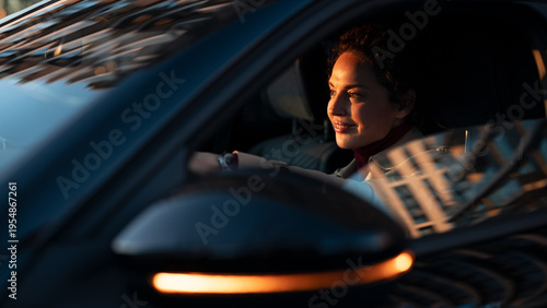 Woman driving car smiling during golden hour commute