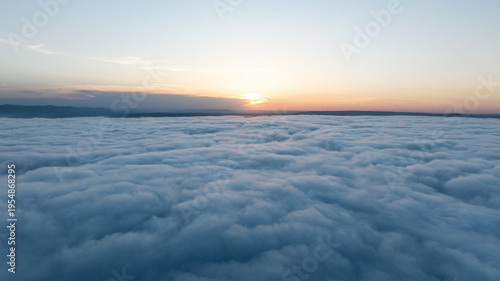Aerial view sunset sky over clouds drone shot. Bright sun disk over thick white cloud layer. Scenic natural phenomenon high altitude photography environment scenery background