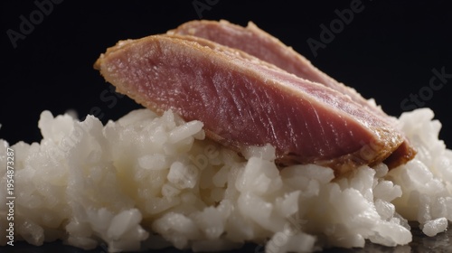 Sliced Gourmet Duck Breast Positioned Elegantly on a Bed of Steamed White Rice Against a Dark Background for Culinary Inspiration