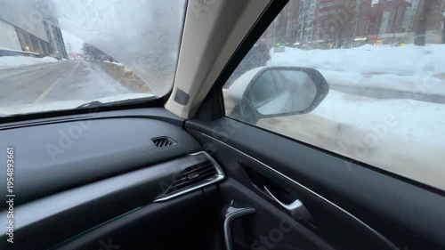 View from a car on a snowy winter road, wet snow on roadside, urban environment, harsh cold winter drive, traffic and safety, city winter conditions