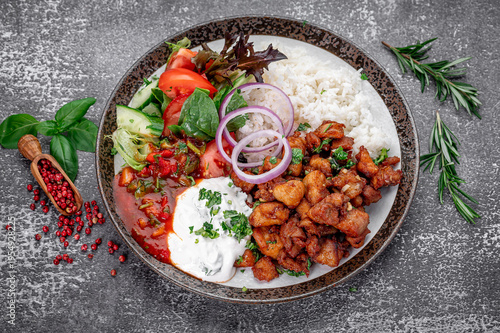 Delicious fried chicken served with rice and fresh salad on a plate. Fried chicken pieces are arranged on a plate with rice and fresh salad on the side.