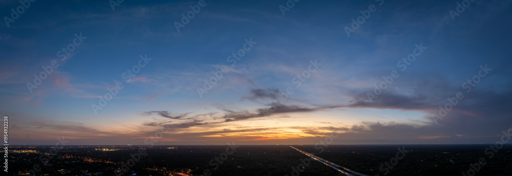 Fototapeta premium Sunset sky over dark land. Bright colorful orange and yellow clouds. Panoramic skyscape