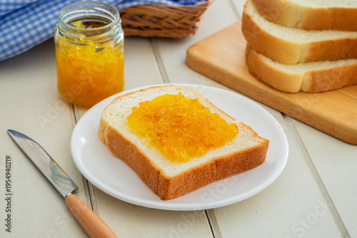 Valokuva Bread slice with orange marmalade jam on white plate