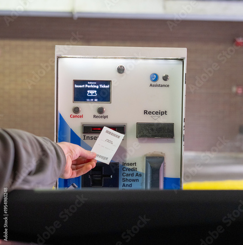 Person inserting parking ticket into automated payment machine