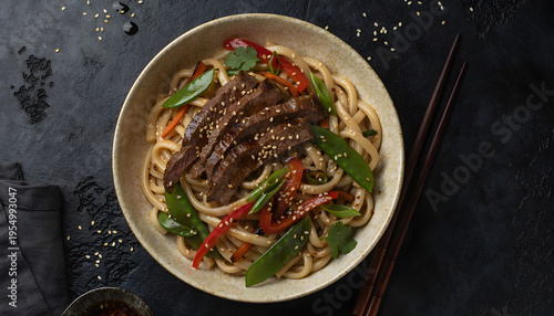 Stir-fried udon noodles with sliced beef and vegetables in a bowl
