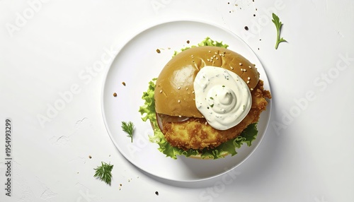 Overhead view of a golden crispy chicken burger with creamy sauce on a white plate studio shot for restaurant menu and food photography