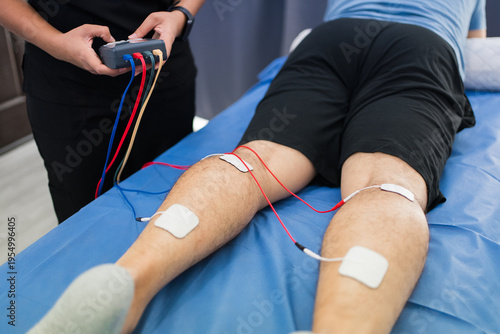 фотографія Therapist providing electrical muscle stimulation for leg pain rehabilitation
