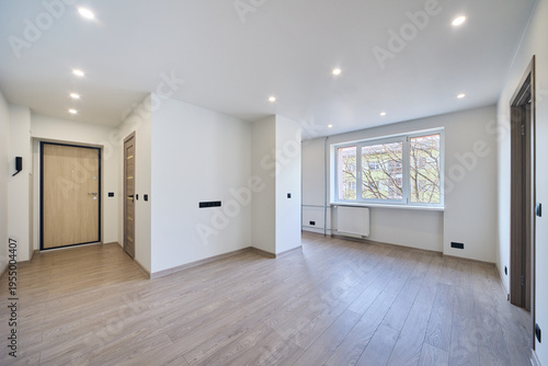 Modern empty apartment interior ready for sale or rent. Bright minimalistic hallway with wooden floor in a new residential building. Real estate investment, property development and housing market.