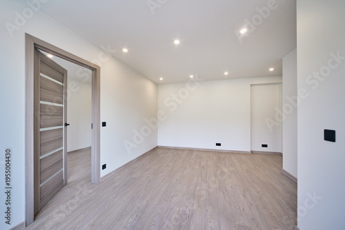 Modern empty apartment interior ready for sale or rent. Bright minimalistic hallway with wooden floor in a new residential building. Real estate investment, property development and housing market.